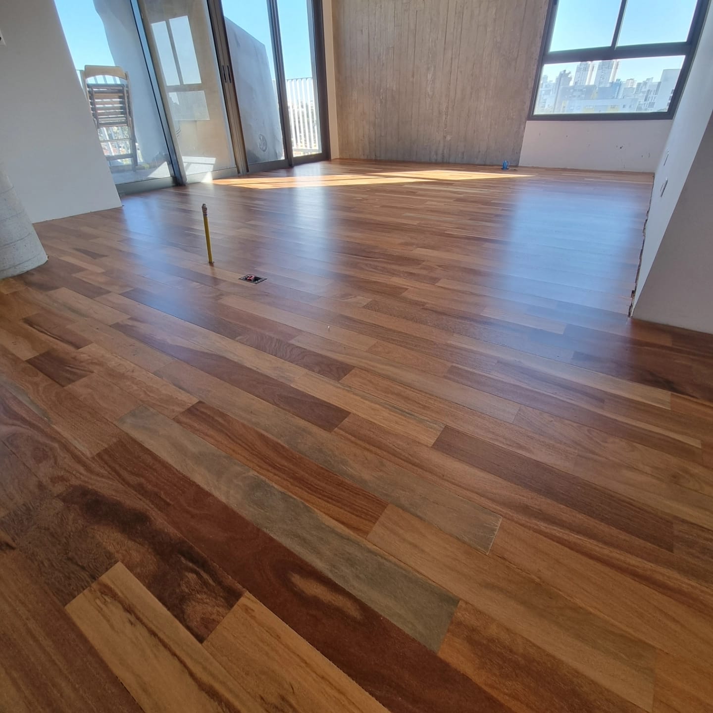 Sala com piso de madeira revitalizado e vista para a cidade
