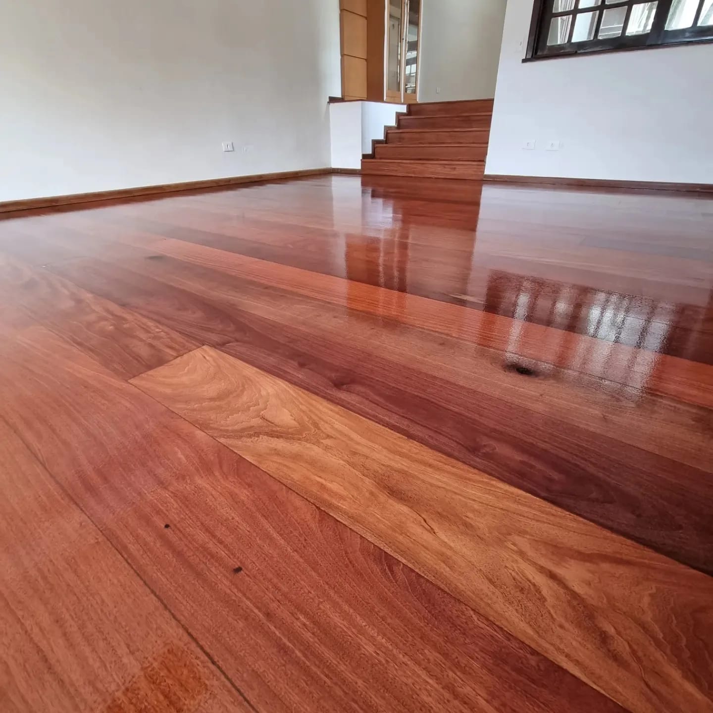 Piso de madeira em espinha de peixe restaurado com escada ao fundo