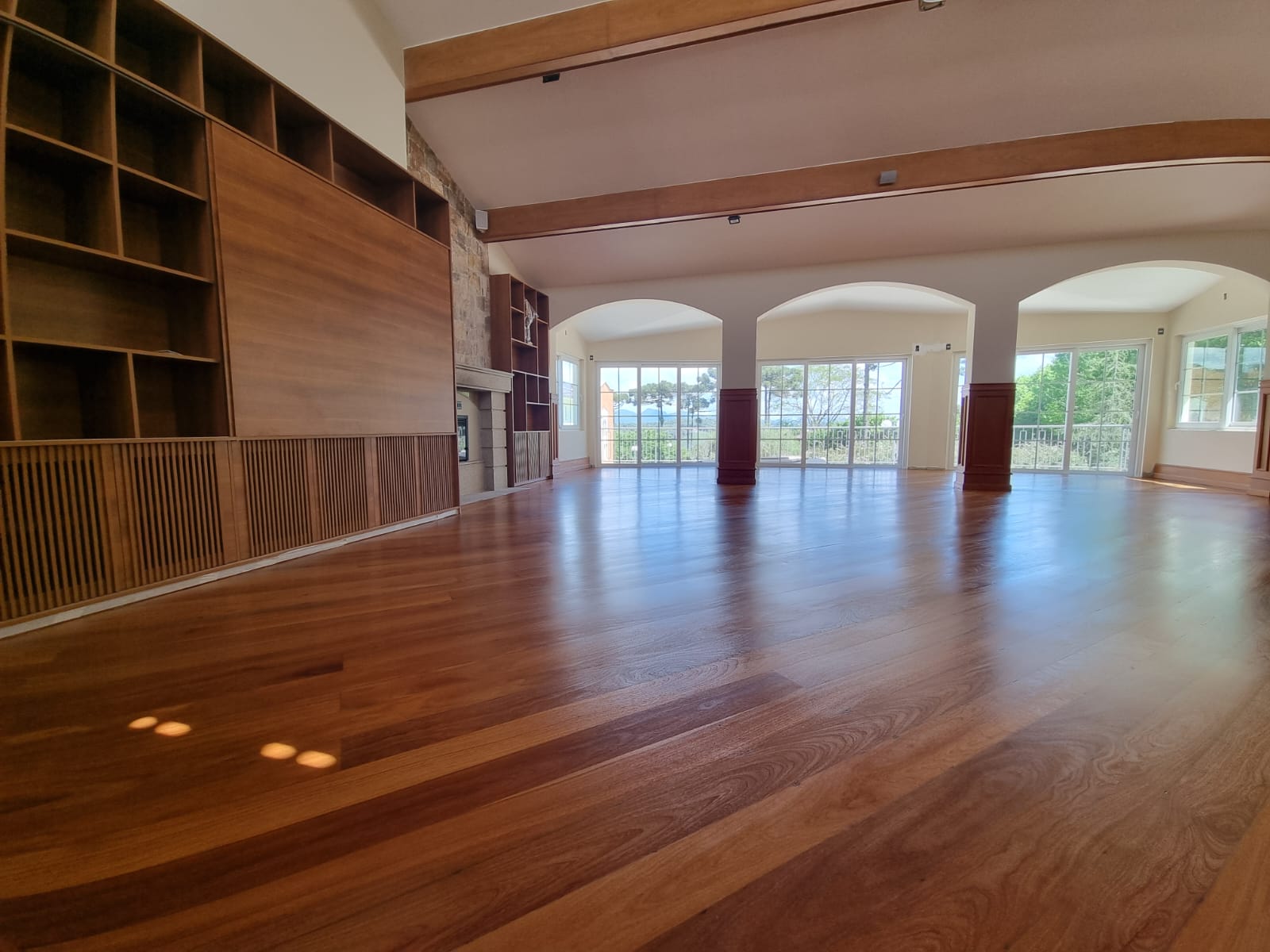 Salão amplo com piso de madeira restaurado e arcos de acabamento