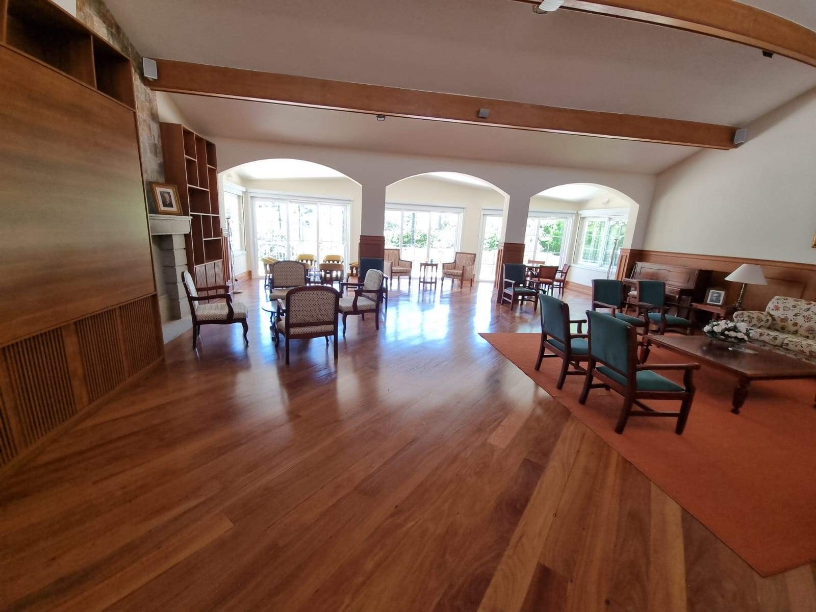 Sala ampla com piso de madeira restaurado, lareira e mobiliário clássico